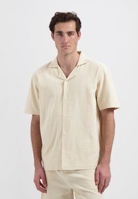 Korte mouwen, lichtbeige overhemd met knopen en een gestructureerde afwerking, met een ingesneden kraag, witte knopen en een relaxte pasvorm.