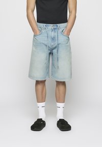 Gai zila denim šorti ar brīvu piegriezumu, pieci kabatas, pogu aizdare un aukla. Valkāti ar baltām zeķēm un tumšām kurpēm.