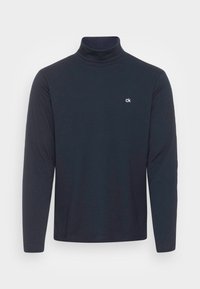 Marinblå polotröja i mjukt material, med långa ärmar och en liten vit logotyp på bröstet. Enkel, figurnära design.