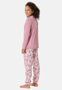 Rosa Langarmshirt kombiniert mit weißen Schlafanzughosen mit einem bunten Herzmuster. Weicher Stoff, elastische Bündchen und Bund.