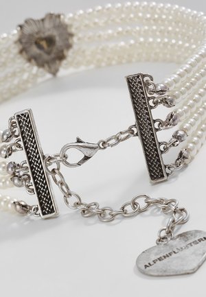 Fermoir et chaîne en argent avec plusieurs rangées de petites perles blanches sur un bracelet, incluant une étiquette en forme de cœur avec texte gravé.