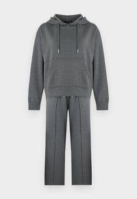 Γκρι φούτερ με κουκούλα, εμπρόσθια τσέπη και κορδόνια, σε συνδυασμό με αντίστοιχο παντελόνι με φαρδιά μπότα και κάθετες ραφές. Υφαντό από βαμβακερό μείγμα.