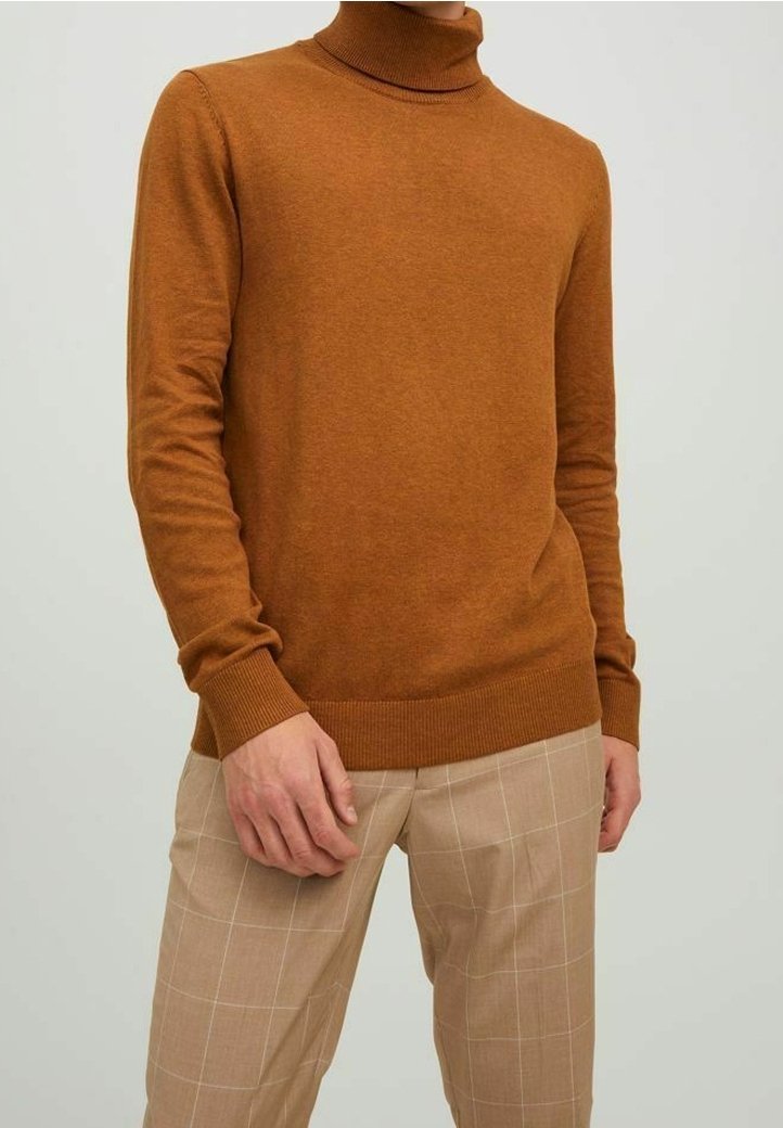 Turtlenecktröja i varm brun ullblandning, med långa ärmar och ribbade ärmslut, parat med ljus beige rutiga byxor.