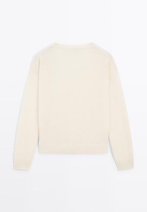 Pull beige clair à manches longues, col rond, avec des poignets et un ourlet côtelés. Texture douce, design simple et sans motifs visibles.
