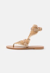 Tan suede sandaali, jossa on avonainen varvas, koristeelliset helmet ja brodeeraus. Ominaisuuksiin kuuluu T-nauhasuunnittelu ja säädettävä nilkkatalje.