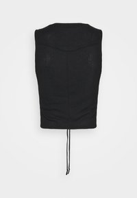 Top nero senza maniche in maglia con una delicata texture a coste, un dettaglio a cucitura a V sulla parte superiore della schiena e un laccio che pende dall'orlo.