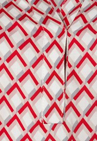 Cotton fabric featuring a geometric pattern in red, gray, and white. Design includes interlocking shapes with a smooth texture.