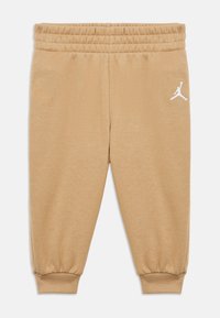 Μπεζ παντελόνι φόρμας με ελαστική μέση και μανσέτες. Διαθέτει λευκό λογότυπο Jumpman στο πλάι. Κατασκευασμένο από απαλό ύφασμα.