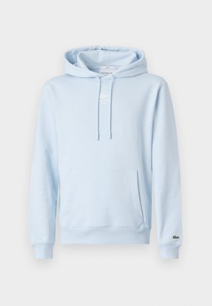 Hellblaue Kapuzenjacke aus weichem Baumwollmaterial. Verfügt über eine Fronttasche und ein kleines gesticktes Logo auf der Brust. Klassischer Schnitt mit gerippten Manschetten.