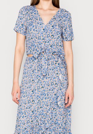 Blumiges Zweiteiler-Outfit mit blauem Hintergrund, orangefarbenen und weißen Gänseblümchen, kurzen Ärmeln, einem gebundenen Taillenbereich und einem schichten Rock.