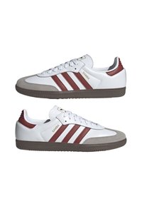 Baskets en cuir blanc avec des rayures rouge et blanche, embout en daim gris et semelle en caoutchouc. Présente un logo sur le côté et la languette.