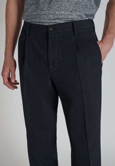 Pantaloni blu navy realizzati in un tessuto morbido, con fronte piatto, pieghe, tasche laterali e chiusura con bottone in vita.
