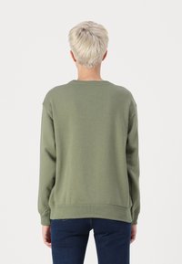 Felpa verde oliva con maniche lunghe, scollatura a girocollo a costine e una vestibilità rilassata. Il tessuto sembra morbido e leggermente strutturato. Nessun motivo visibile.