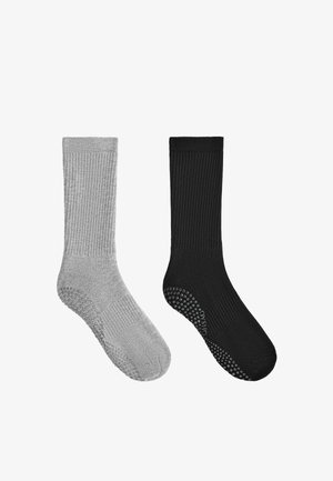 Paar gerippte Crew-Socken, eine hellgrau und eine schwarz, jeweils mit strukturierten rutschfesten Sohlen.