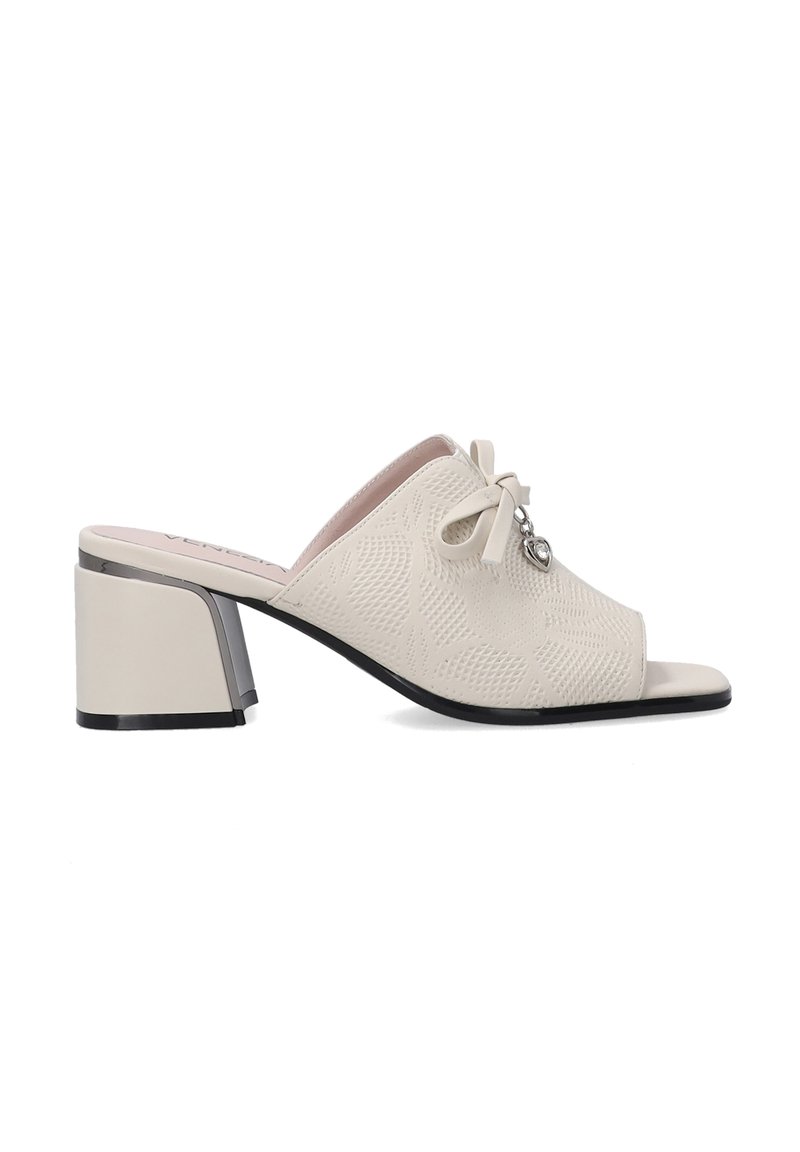 Crème open-toe mules met een gestructureerde bovenkant, strikdetail en een blokhak met een metallic accent. De zool is zwart met een gladde afwerking.