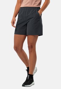 Anthrazitgraue Sportshorts mit einem elastischen Bund, seitlichen Taschen und einer lockeren Passform, kombiniert mit schwarzen Sneakers und Socken.