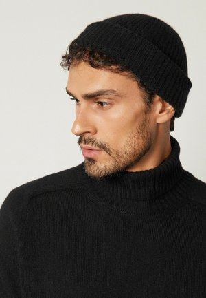 Czarna prążkowana czapka beanie oraz czarny sweter z golfem, charakteryzujący się teksturowanym materiałem i dopasowanym krojem. Minimalistyczne elementy projektu.