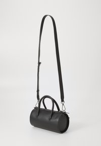 Sac à main cylindrique en cuir noir avec une finition texturée, anses supérieures doubles et bandoulière amovible. Équipé de quincaillerie en ton argent.