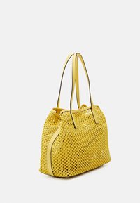 Sac fourre-tout en maille jaune avec des détails en cuir et des doubles poignées. Motif texturé sur l'ensemble, forme structurée et design à ouverture supérieure.