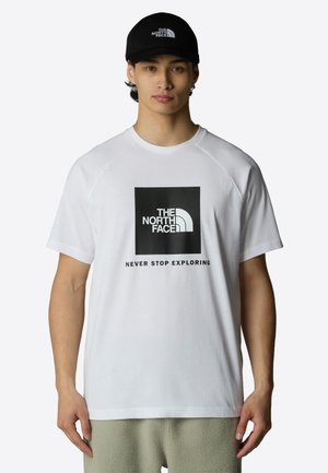 Camiseta blanca de manga corta con un gráfico negro centrado en el pecho que dice "THE NORTH FACE" y "NEVER STOP EXPLORING" debajo.