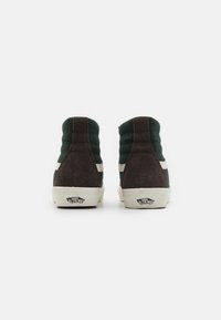 High-top sneakers in dark green and brown suede, featuring padded sides, white stripes, and off-white rubber soles with branding.