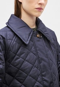 Ναυτικό μονωμένο μπουφάν με μεγάλο γιακά, με κουμπιά και λοξό μοτίβο ραφής. Μαλακό, ελαφρύ ύφασμα με ομαλή υφή.