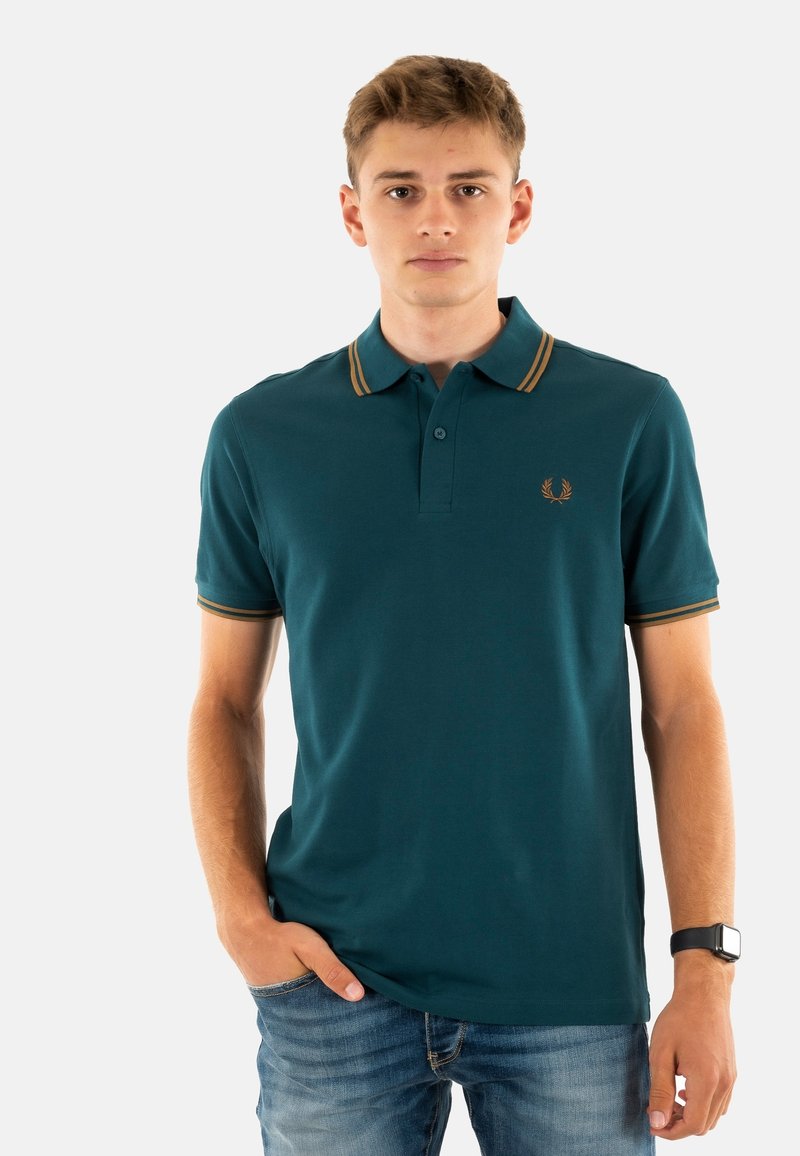 Polo shirt in diep teal met een klassieke kraag, een placket met twee knopen en horizontale strepen in goud. Heeft een klein logo op de borst.