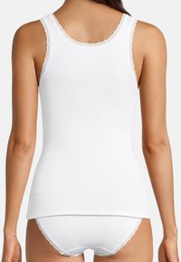 Top in cotone bianco senza maniche con pizzo lungo il collo e i fori per le braccia, abbinato a slip bianchi coordinati. Texture liscia, design attillato.