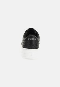 Sneaker nera con motivo in rilievo, suola bianca e logo "GUESS" sul tallone. Caratterizzata da un collare imbottito per il comfort.
