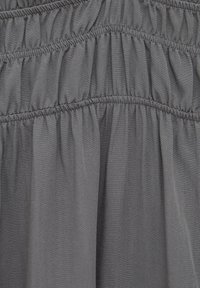 Tissu gris avec une texture lisse, comportant des plis froncés et des coutures élastiques en bandes horizontales. Matériau doux et léger.