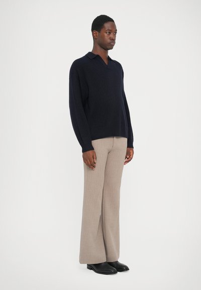 Navy ribbed knit polo sweater with a relaxed fit, paired with light beige wide-leg trousers and black leather shoes.