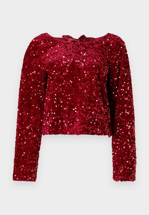 Haut à manches longues en sequins rouges avec un col rond et un détail noué à l'arrière. Le tissu a une finition brillante et texturée.