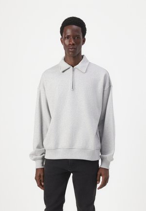 Sweatshirt cinza com colarinho com fecho, corte solto, punhos canelados e cintura elástica. Textura suave e design minimalista.
