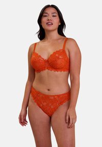 Set di bralette in pizzo e slip coordinati di un vivace arancione. Presenta motivi floreali, bordi ondulati, spalline regolabili e dettagli delicati.