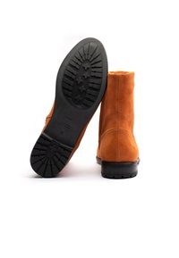 Stivaletti alla caviglia in suede arancione con finitura liscia, suola in gomma dotata di battistrada scanalato per una migliore trazione e design della punta arrotondata.