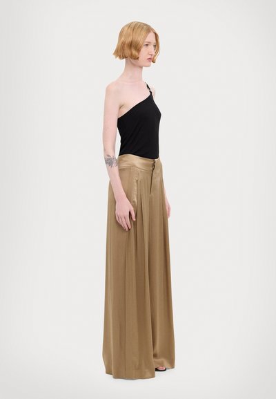 Top nero a costine con spallina unica abbinato a pantaloni beige in satin alta vita e a gamba larga con pieghe e chiusura con bottone frontale.