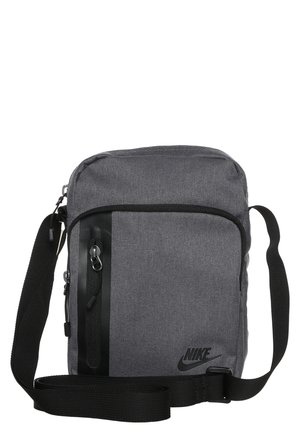 Graue Nike Crossbody-Tasche mit schwarzem verstellbarem Riemen, vorderer Reißverschlusstasche und schwarzem Nike-Logo unten rechts.