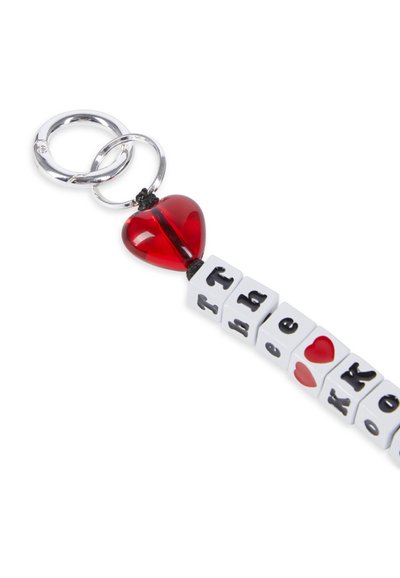 Sleutelhanger met zilveren metalen ringen, een rode hartkraaltje en witte blokken met zwarte en rode letters. Ontworpen met een speelse, kleurrijke esthetiek.