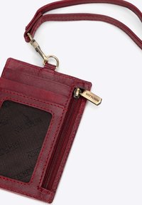 Rode leren ID-houder met ritsvak, voorzien van een doorzichtige venster en decoratieve stiksels. Messing hardware met een clip.