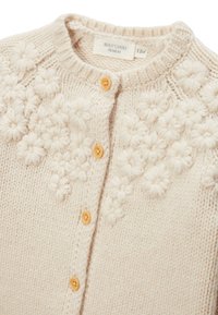 Cardigan crème avec motifs floraux tricotés, encolure ronde et boutons en bois clair. Fabriqué à partir d'un fil doux et texturé. Taille 12 mois.