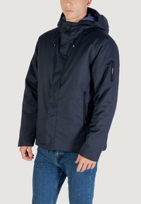 Giacca blu navy con cappuccio, dotata di una zip frontale, due tasche laterali, una superficie liscia e cordini regolabili sul cappuccio.