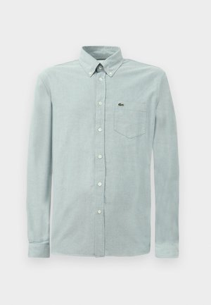 Light blue button-up shirt made of soft fabric, featuring a collar, long sleeves, and a chest pocket with a small logo.