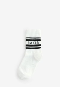 Weißer Baumwollsocken mit gerippter Textur, ausgestattet mit schwarzen Akzentstreifen und "BAKER" in Schwarz auf dem oberen Bündchen gestrickt. Standard Länge für Crew-Socken.