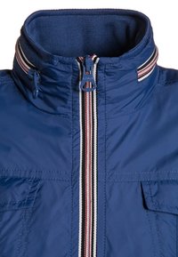 Modrá límec bundy se pruhovaným zipem a odpovídajícím pruhovaným detailem na okraji límce, se dvěma předními kapsami s klopou.