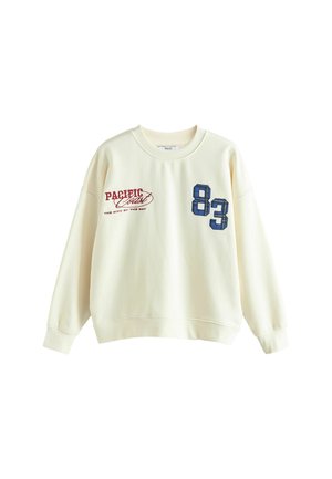 Kermasvärinen collegepaita pyöreällä kaula-aukkolla, pitkät hihat, jossa etupuolella punaiset ja siniset graafiset tekstit sekä kuvioitu numero "83".