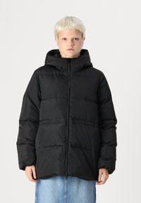 Juodas pūkinis švarkas su kapišonu, turintis užtrauktuko uždarymą ir horizontalų siūlų raštą. Atrodo, kad audinys yra lygus ir izoliuotas.