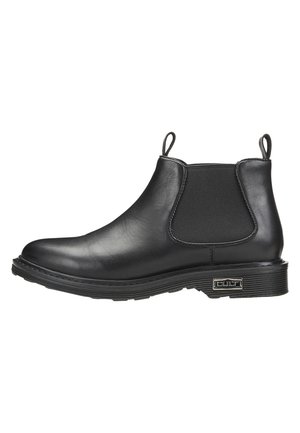 Stivale Chelsea in pelle nera con pannelli elastici laterali e linguette per il trasporto. Suola in gomma spessa con texture rigata e piccolo logo laterale.