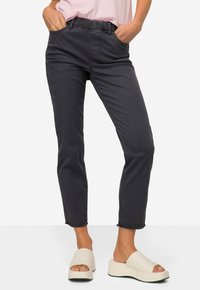 Grijze, taps toelopende jeans met een elastische tailleband en zijzakken. Gemaakt in combinatie met witte platform sandalen. Glad texture en casual ontwerp.