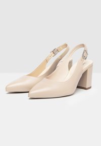 Escarpins à brides beiges avec un bout pointu, texture en cuir lisse, sangle réglable avec boucle et un solide talon bloc.
