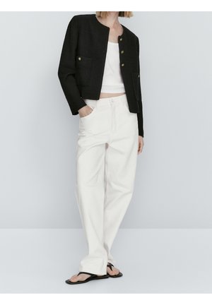 Czarna krótka kurtka z złotymi guzikami i dwoma przednimi kieszeniami, zestawiona z białymi spodniami o szerokich nogawkach i czarnymi klapkami.